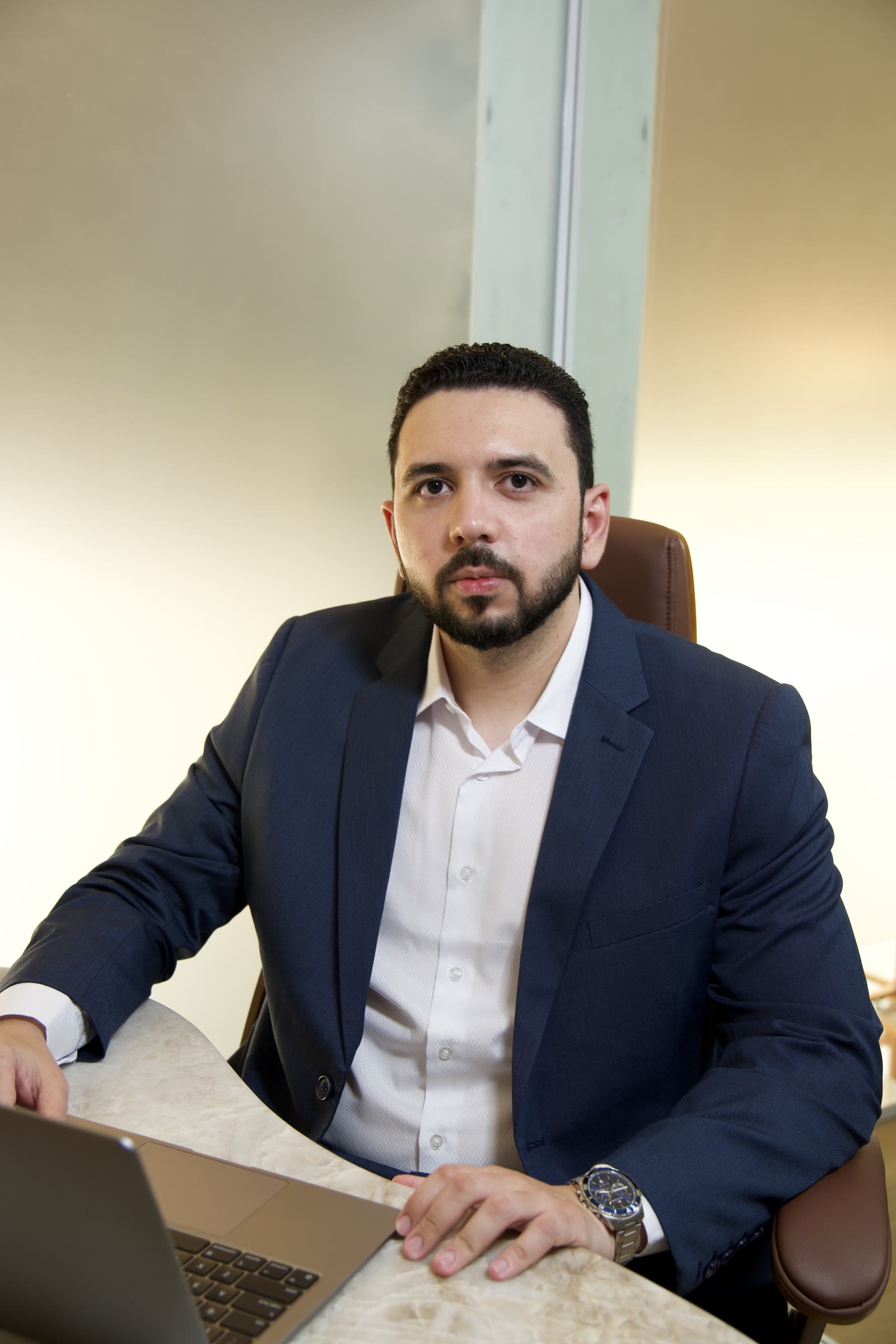 Dr. Clenilson Júnior de terno escuro, sentado à mesa do consultório durante um atendimento